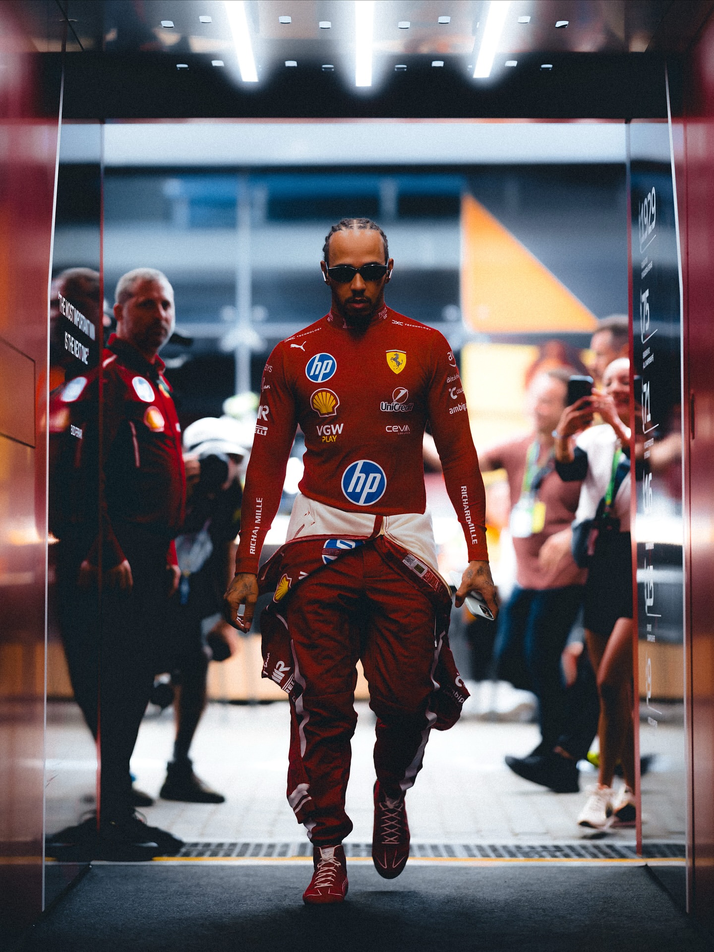 Lewis Hamilton walking in Ferrari race gear ahead of a Grand Prix