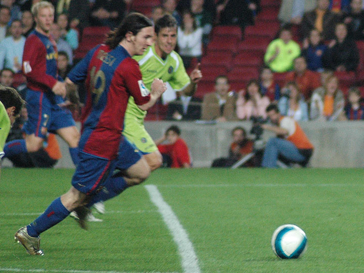 young Lionel Messi dribbling for Barcelona in an early career match