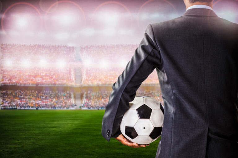 Rear View Of Businessman Holding Soccer Ball While Standing In Stadium