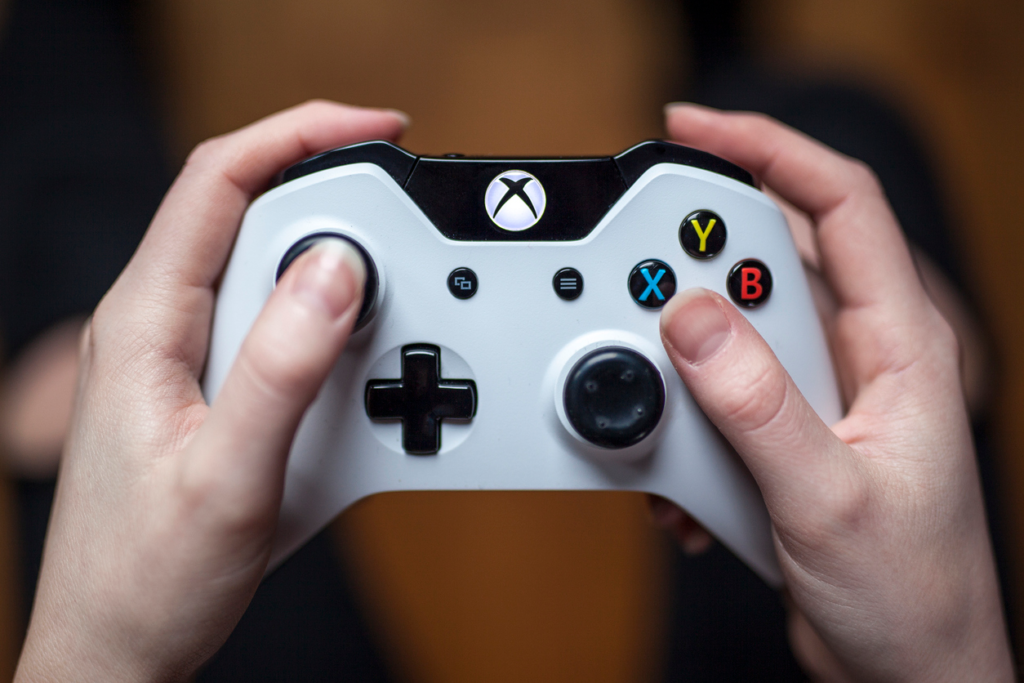 Close-up of a hand holding a white Xbox controller, symbolizing Xbox Live
