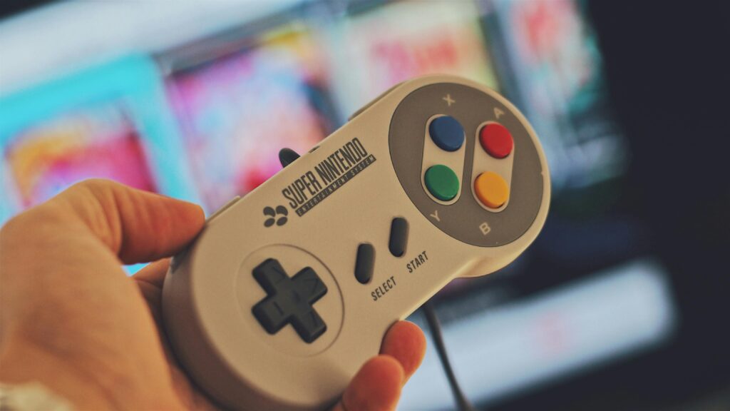 hand holding a Super Nintendo controller in front of a TV