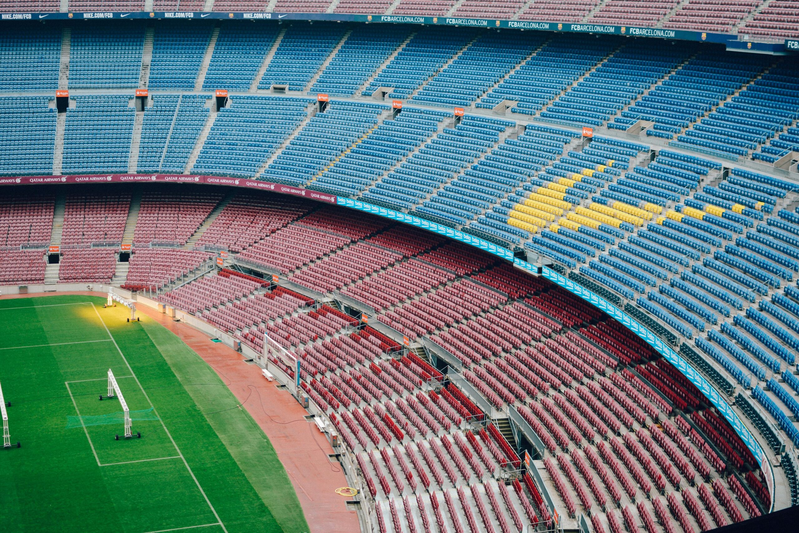 Wide view of FC Barcelona’s Camp Nou stadium with empty multicoloured seating and a clear look over the pitch.