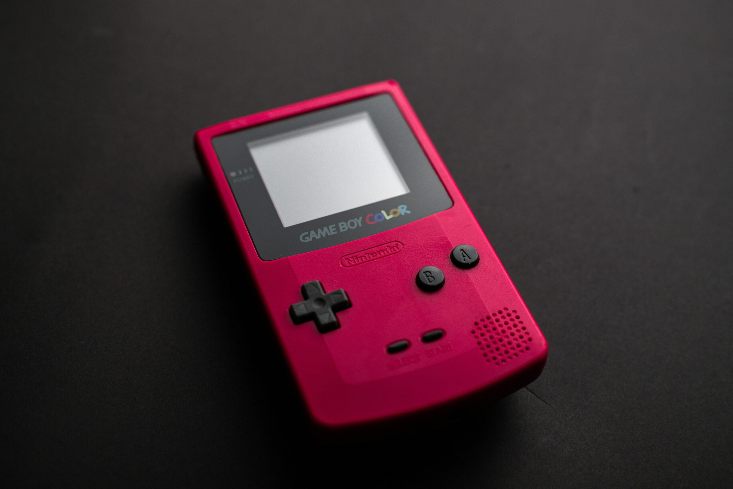 Red Nintendo Game Boy Color handheld console placed on a dark surface.