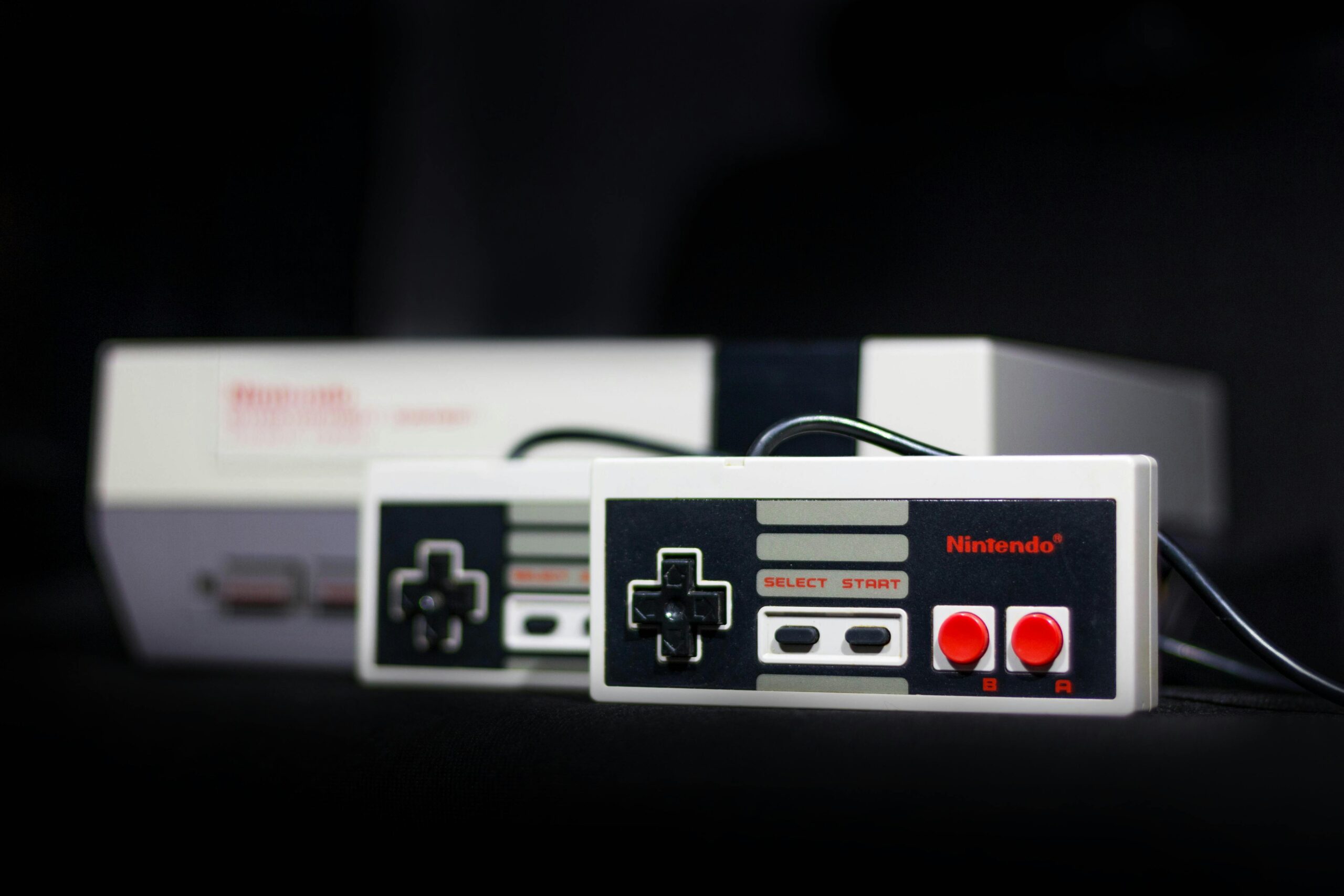 two Nintendo NES controllers placed in front of the NES console