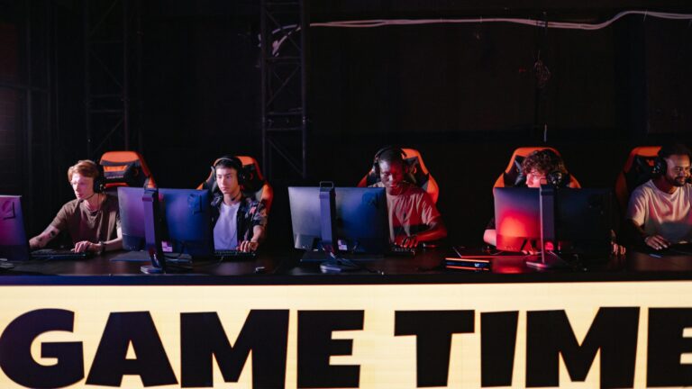 Esports team of five players competing together at computer stations in a tournament setting.