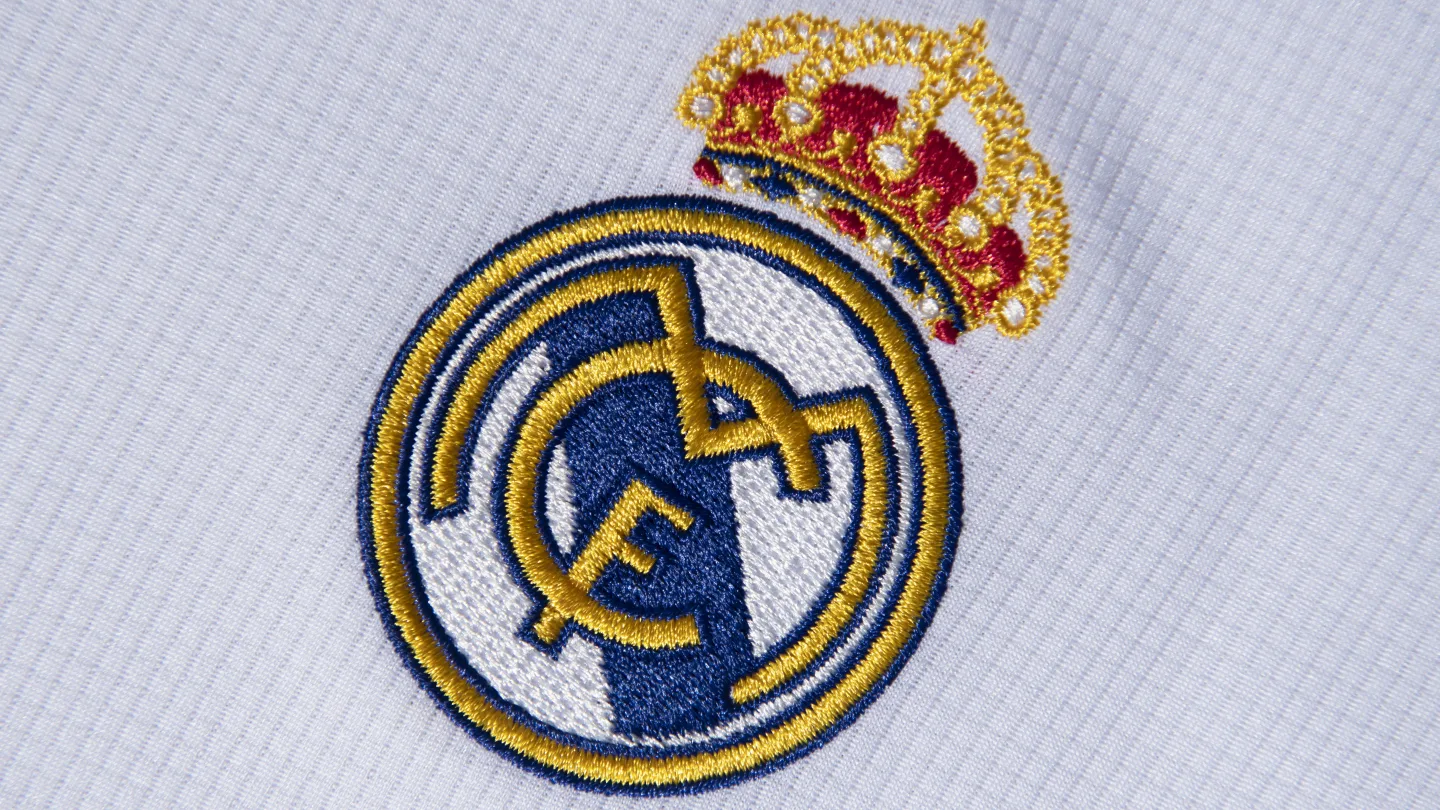 Real Madrid club badge featuring the royal crown and intertwined “MCF” initials on a white and gold crest.