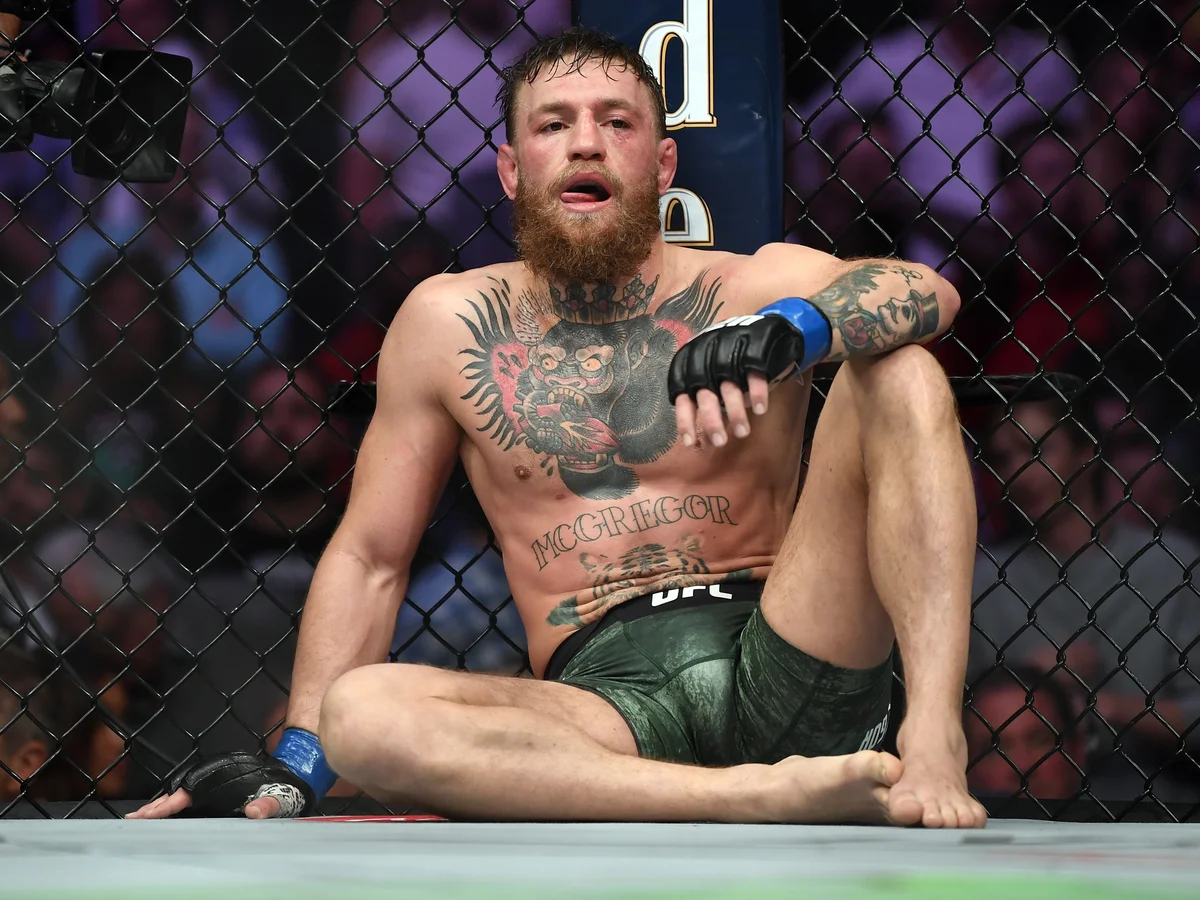 Conor McGregor sits against the cage inside the UFC Octagon during a fight.