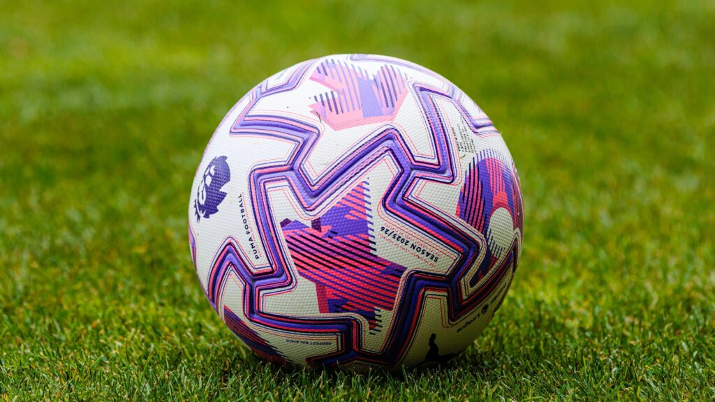Close up of the official Premier League 2025 26 match ball with a purple and pink Puma design resting on the pitch.