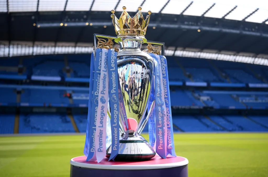 Premier League trophy displayed on the pitch inside an empty stadium