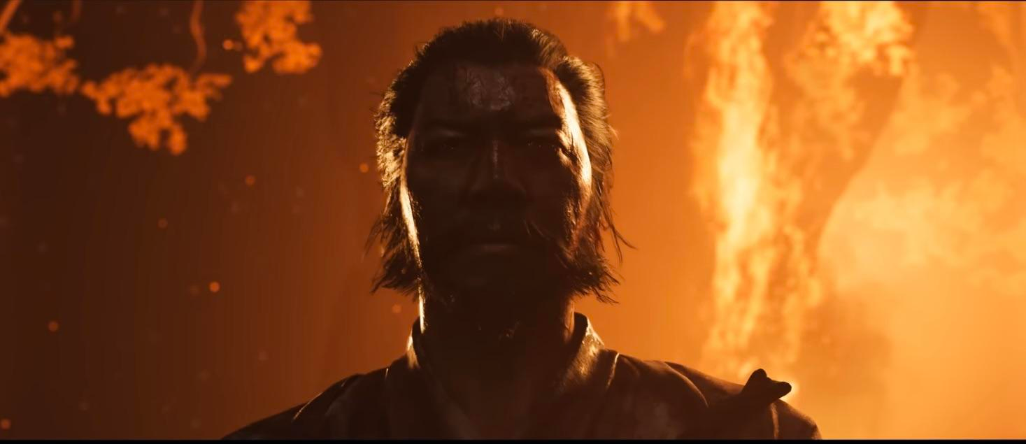 Close-up of Lord Saito from Ghost of Yōtei, his face framed by flames, representing his menacing presence and the central threat in Atsu’s revenge story.