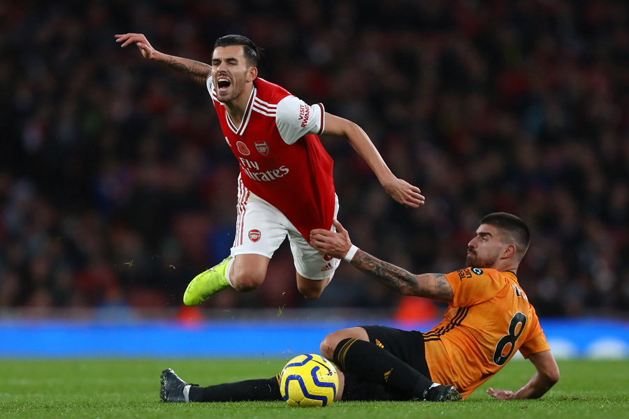 Arsenal midfielder challenged by Wolves defender during a physical Premier League match at the Emirates Stadium