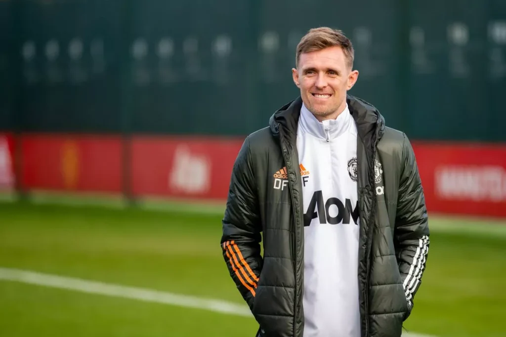 Darren Fletcher wearing Manchester United coaching gear on the sidelines during his previous tenure with the first team, focused on guiding players.