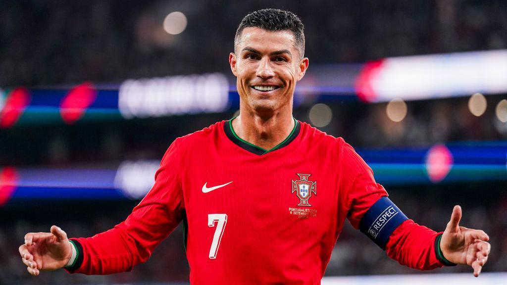 Cristiano Ronaldo smiling after scoring a goal for Portugal, radiating joy and national pride during an international match.